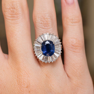 Close-up of a vintage 18ct white gold ring with a rich blue sapphire encircled by a fan of baguette-cut diamonds.