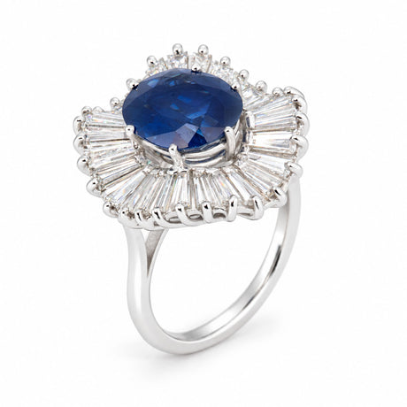 Angled product view of a vintage sapphire cocktail ring, featuring a deep blue centre stone framed by radiating baguette-cut diamonds.