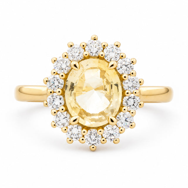 An antique-inspired, pale yellow sapphire and diamond cluster engagement ring set in 14ct yellow gold. 
