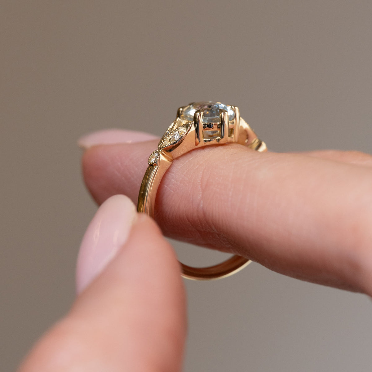 Side profile of the vintage-inspired engagement ring, revealing the open gallery, decorative gold shoulders and polished yellow gold band.