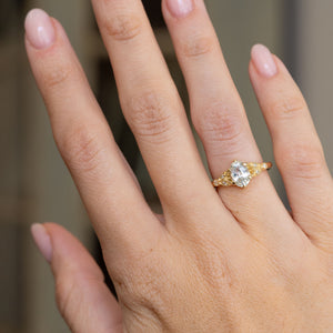 Vintage-style sapphire and diamond engagement ring worn on the hand, showing its elegant scale and bright yellow gold finish.