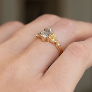 Three-quarter hand view revealing the elevated sapphire setting, openwork shoulders and slender polished band.