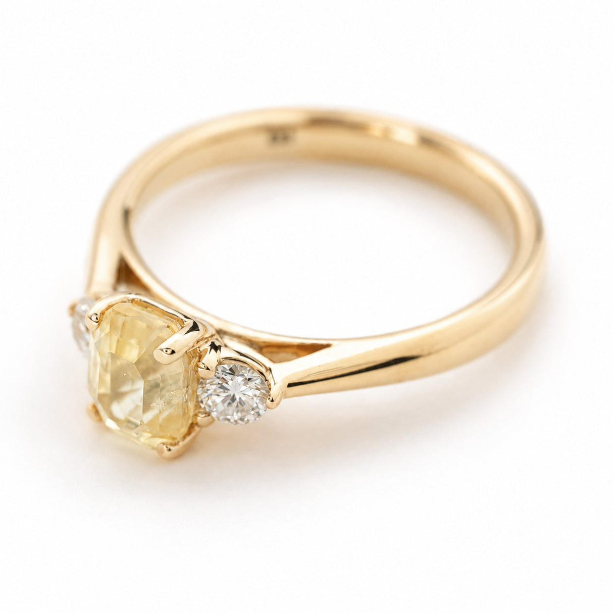A side profile of a vintage-inspired, yellow sapphire and diamond three-stone engagement ring set in yellow gold against a plain white background.