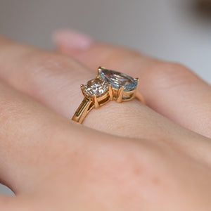 Side-angle view of the toi et moi engagement ring worn on a finger, highlighting the raised gemstone settings and delicate gold band.