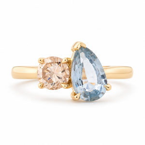 Antique-inspired sapphire and brown diamond toi et moi engagement ring in yellow gold, featuring a pear-cut blue sapphire beside a round champagne-brown diamond.