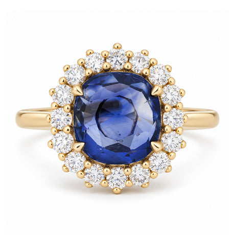 A rich royal blue oval sapphire surrounded by a sparkling halo of round diamonds, set in polished yellow gold.