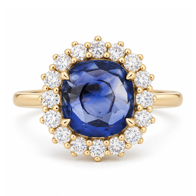 A rich royal blue oval sapphire surrounded by a sparkling halo of round diamonds, set in polished yellow gold.