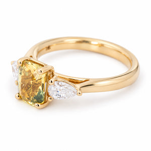 A yellow gold engagement ring with a yellow emerald-cut sapphire at the centre flanked by pear-cut diamonds. 