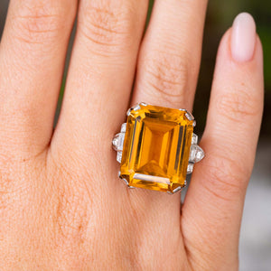 A close-up of a hand wearing an Antique, Art Deco citrine and diamond cocktail ring in platinum.