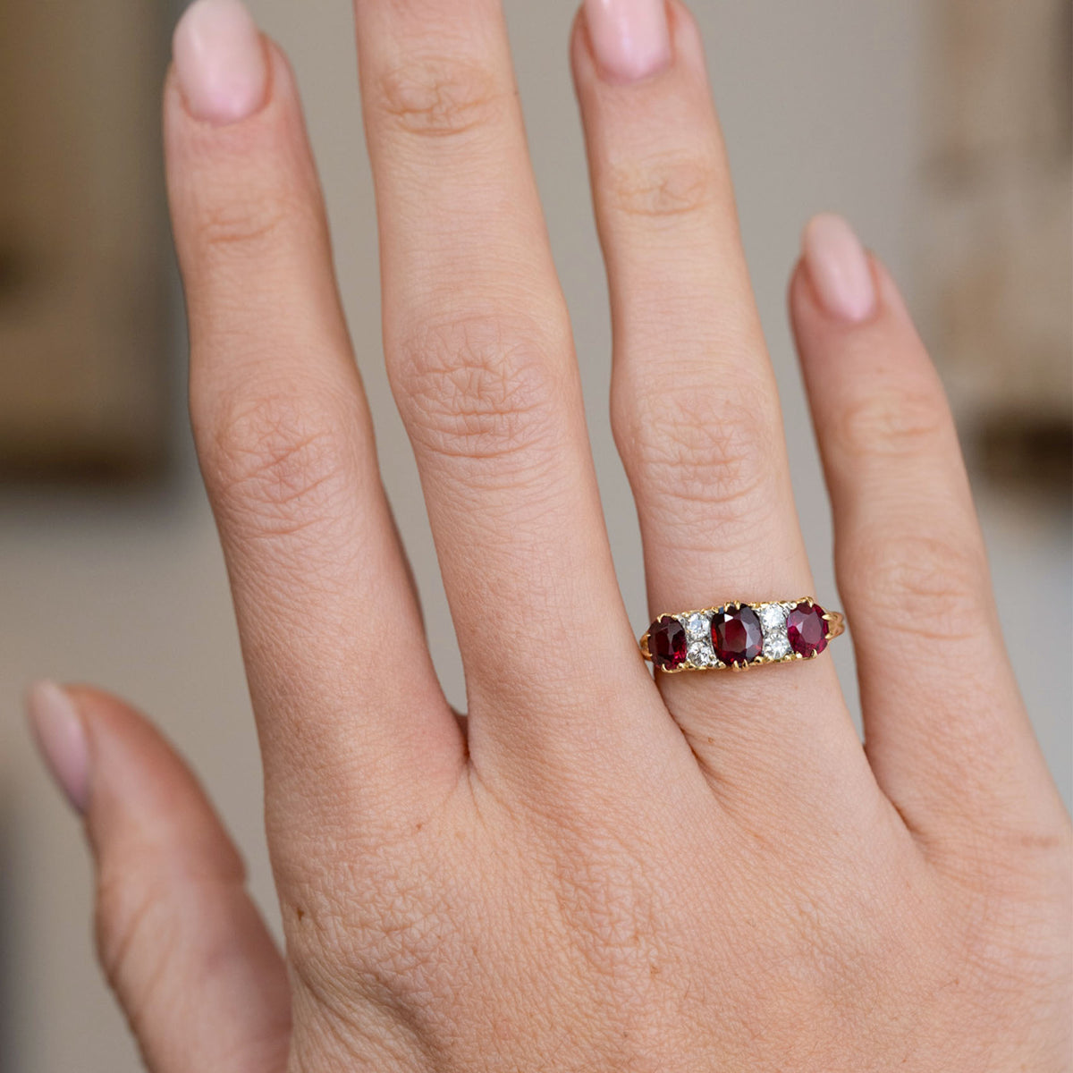 Antique ruby and diamond engagement ring worn on the hand, showing the bold proportions of its Victorian three-stone design.