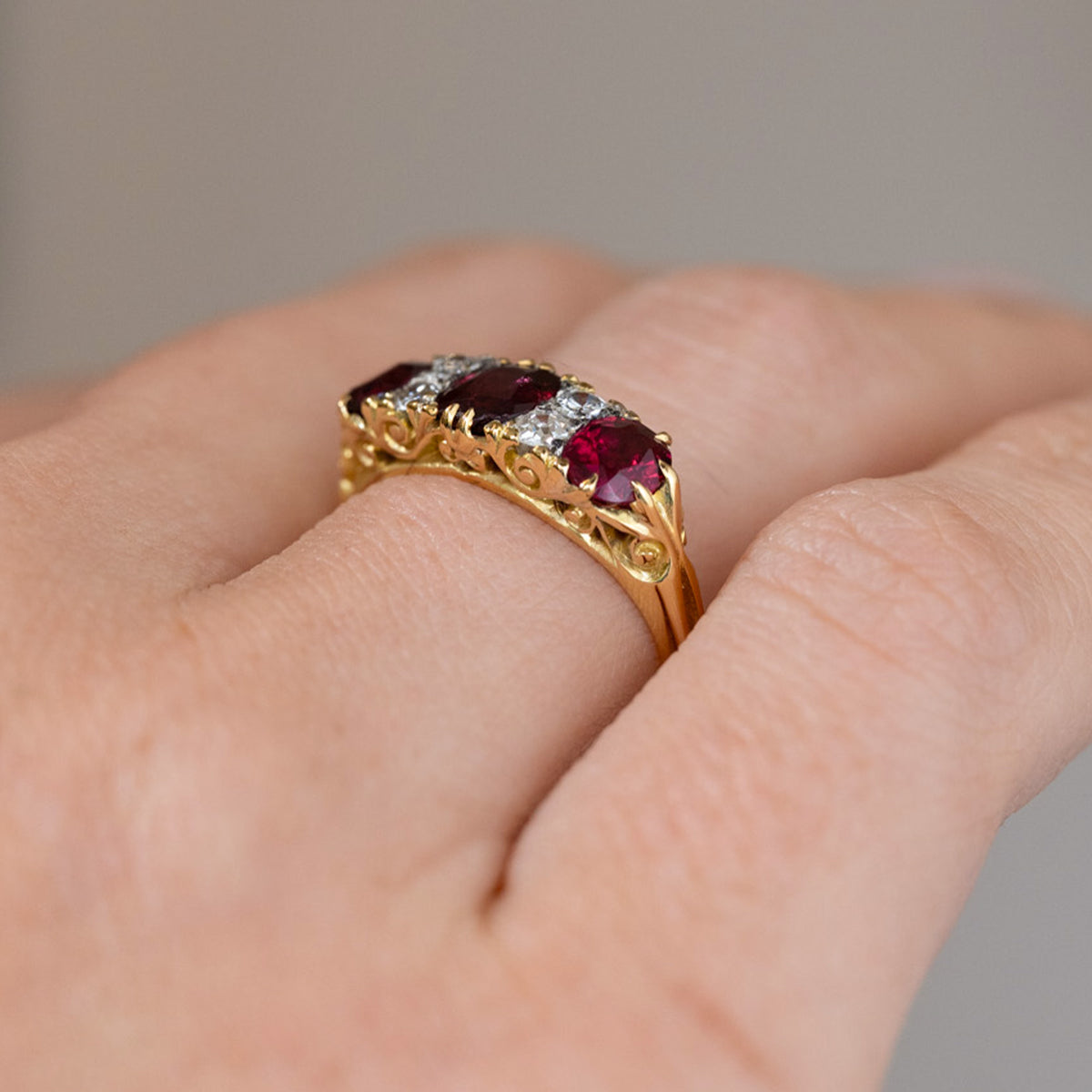 Low side angle of the Victorian ring being worn, revealing the raised gemstones and decorative pierced gold gallery.