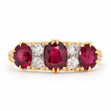 Antique Victorian ruby and old-cut diamond three-stone engagement ring in yellow gold, with three rich red rubies separated by diamond accents.