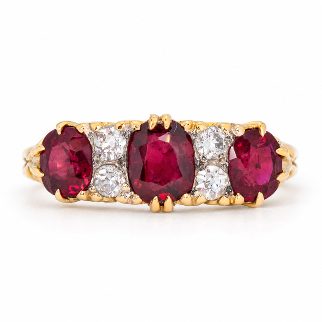 Antique Victorian ruby and old-cut diamond three-stone engagement ring in yellow gold, with three rich red rubies separated by diamond accents.