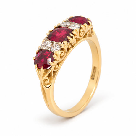 Elevated studio portrait of the Victorian ruby ring, revealing its graduated stones and ornate scrolling yellow gold gallery.