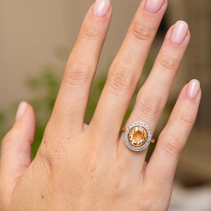 Antique yellow citrine engagement ring worn on the hand, showcasing its oval centre stone and rose-cut diamond surround.
