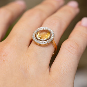 Antique French citrine cluster engagement ring worn at an angle, showing the warm yellow stone and delicate rose-cut diamond border.