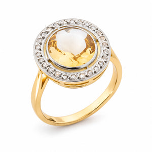 Angled product view of an antique citrine cluster ring, featuring an oval yellow gemstone framed by rose-cut diamonds in platinum.