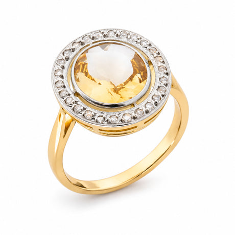 Angled product view of an antique citrine cluster ring, featuring an oval yellow gemstone framed by rose-cut diamonds in platinum.