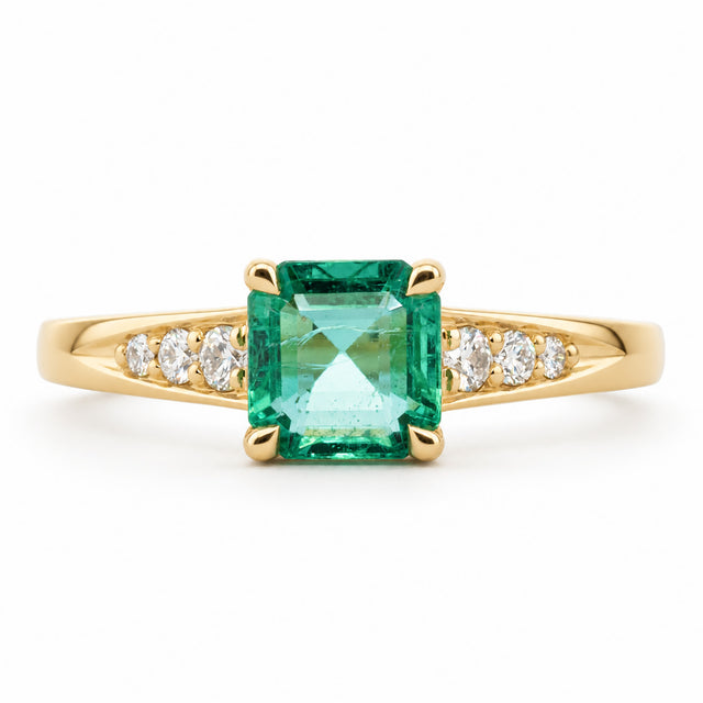 Vintage-inspired, Emerald and diamond flanked solitaire engagement ring with white background