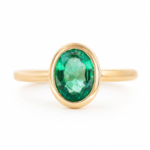 A front profile of an antique-inspired engagement ring in yellow gold set to centre an oval emerald.