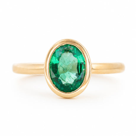 A front profile of an antique-inspired engagement ring in yellow gold set to centre an oval emerald.