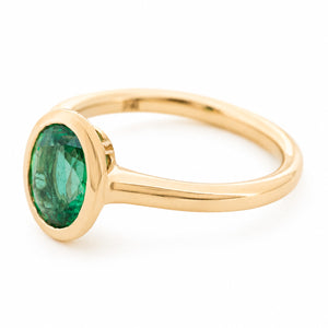 A side profile of a vintage-inspired yellow gold engagement ring featuring an oval emerald.