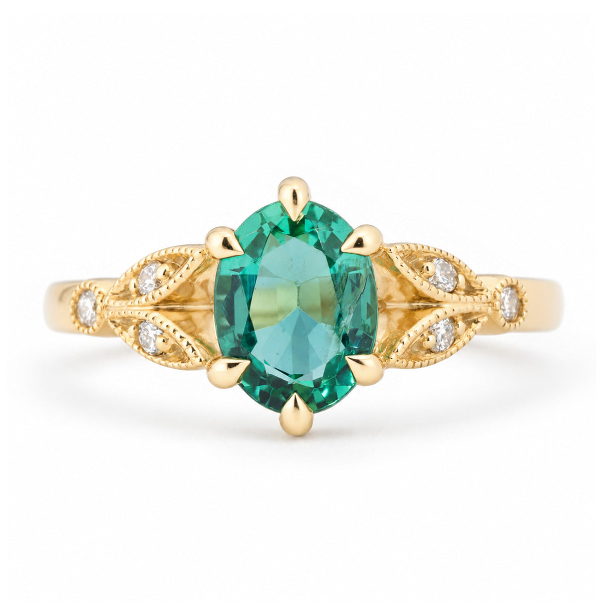 Vintage-inspired emerald and diamond engagement ring in yellow gold, featuring an oval-cut green emerald with intricate laurel leaf-inspired trefoil shoulders and diamond accents.