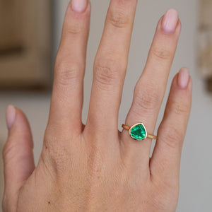 Pear-cut emerald solitaire worn on the hand, showing the vivid green gemstone and elegant vintage-inspired proportions.