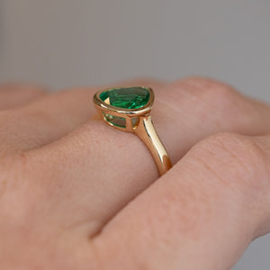 Low side perspective of the ring being worn, revealing its elevated setting, open underside and tapered gold shoulders.