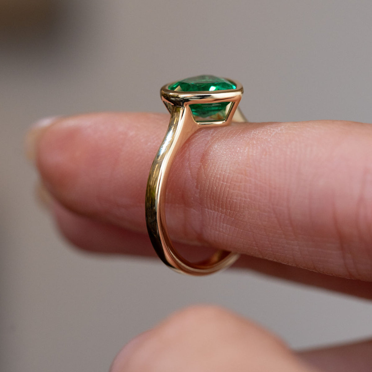 Profile view of the vintage-inspired engagement ring, displaying the raised emerald setting and slender polished shank.