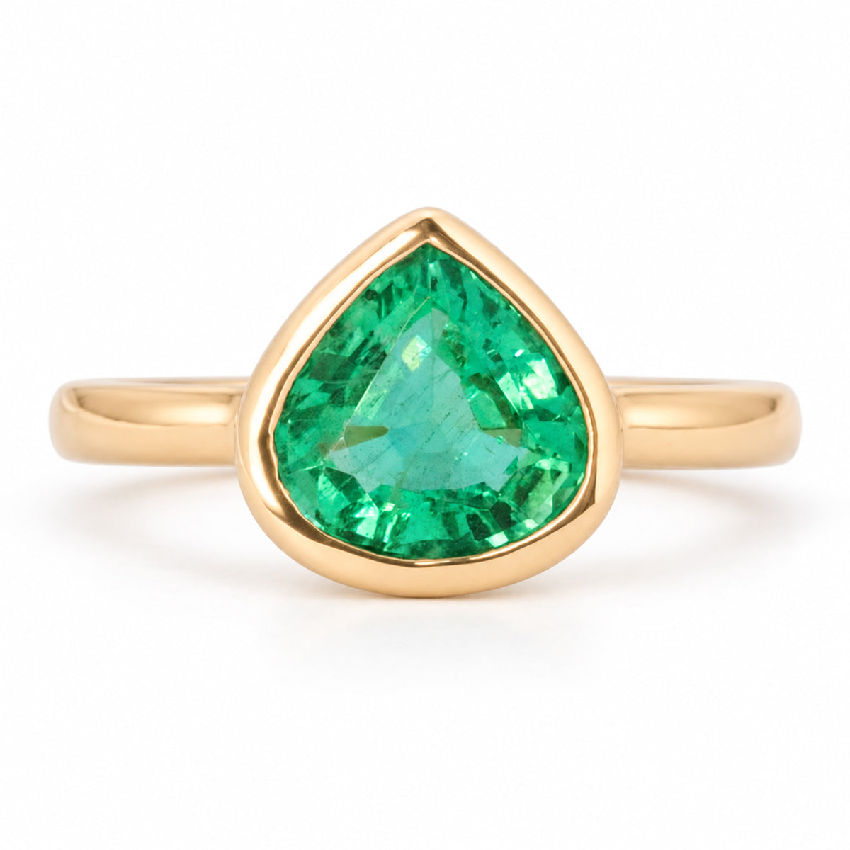Vintage-inspired pear-cut emerald solitaire engagement ring in yellow gold, framed by a smooth rub-over setting.