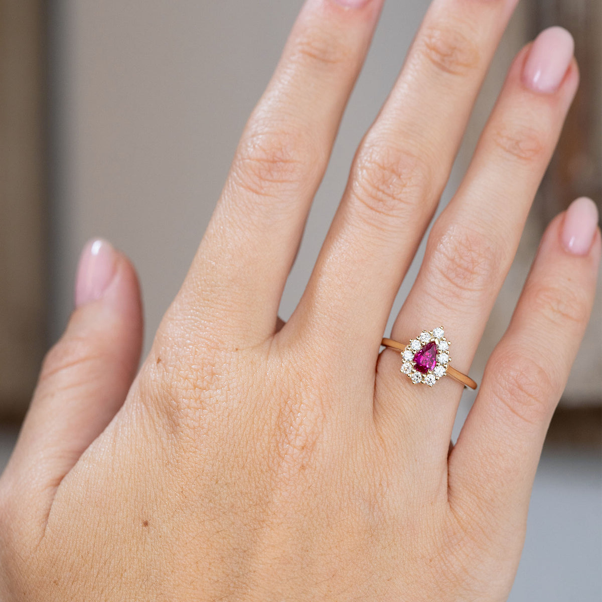 Vintage-inspired ruby and diamond engagement ring worn on the hand, showing its elegant scale and vivid colour.