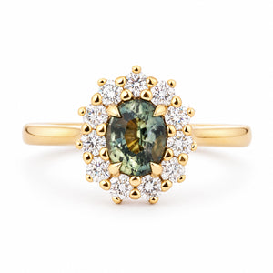 Antique-inspired engagement ring centred with a deep pine green sapphire and encircled by a halo of round diamonds in yellow gold.