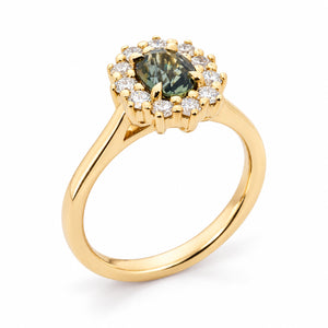 Three-quarter perspective showcasing the oval green sapphire, sparkling diamond cluster and elevated yellow gold basket setting.