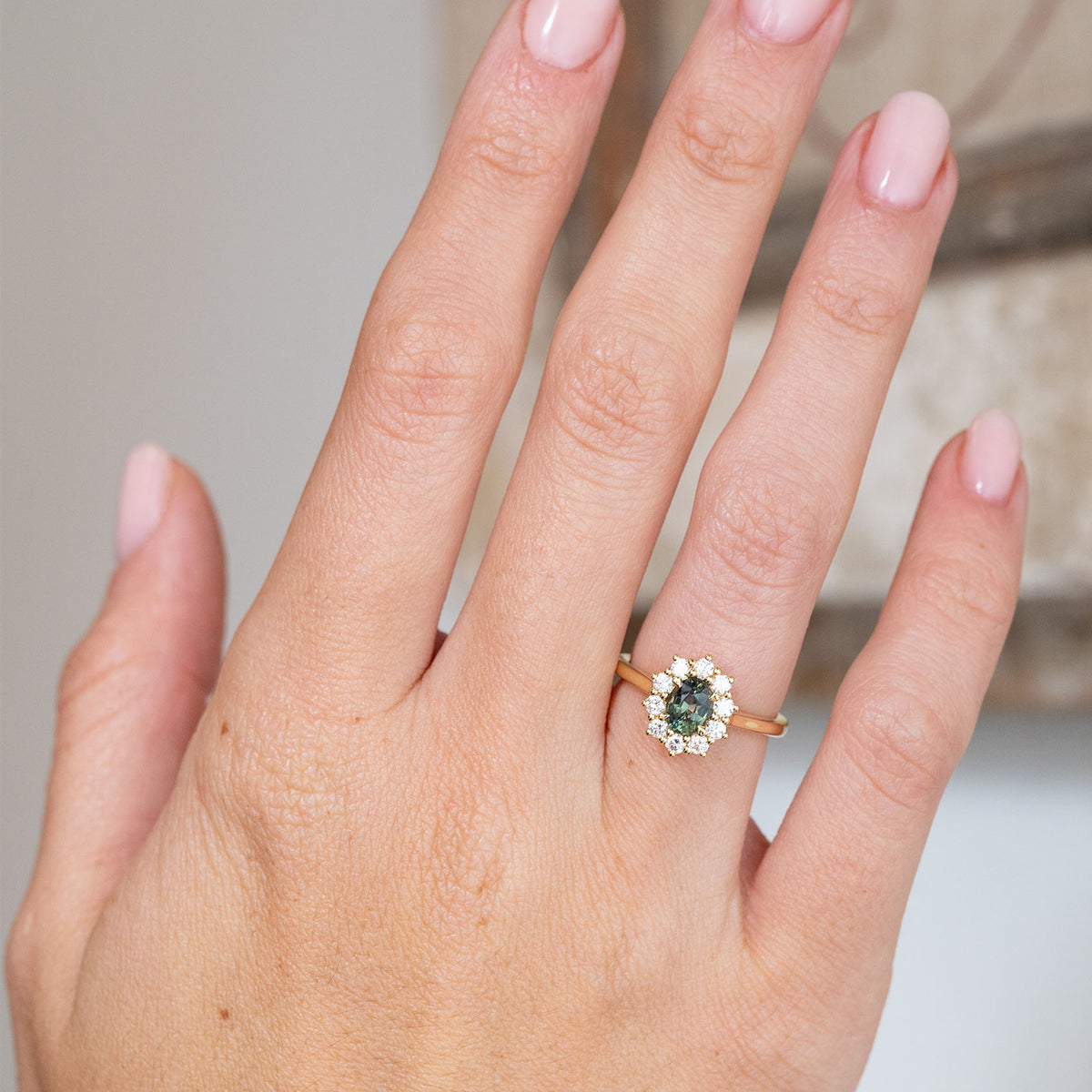 Shown on the hand, the antique-style cluster ring pairs a rich green sapphire with a bright surround of brilliant-cut diamonds.