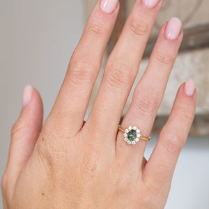 Shown on the hand, the antique-style cluster ring pairs a rich green sapphire with a bright surround of brilliant-cut diamonds.