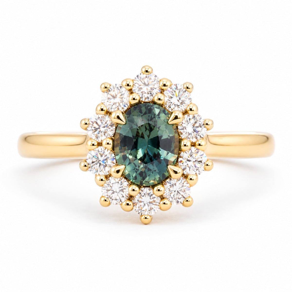 Oval green sapphire framed by a radiant cluster of round brilliant-cut diamonds in this antique-inspired yellow gold engagement ring.