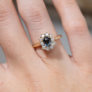 Close-up of the rectangular blue sapphire framed by brilliant-cut white diamonds, worn on a finger.