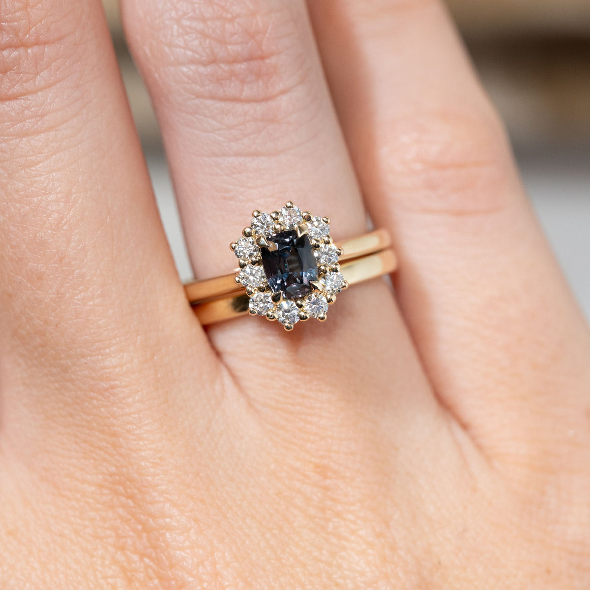 Blue sapphire cluster engagement ring paired with a yellow gold wedding band, showcasing its wed-fit design and how the two rings sit together.