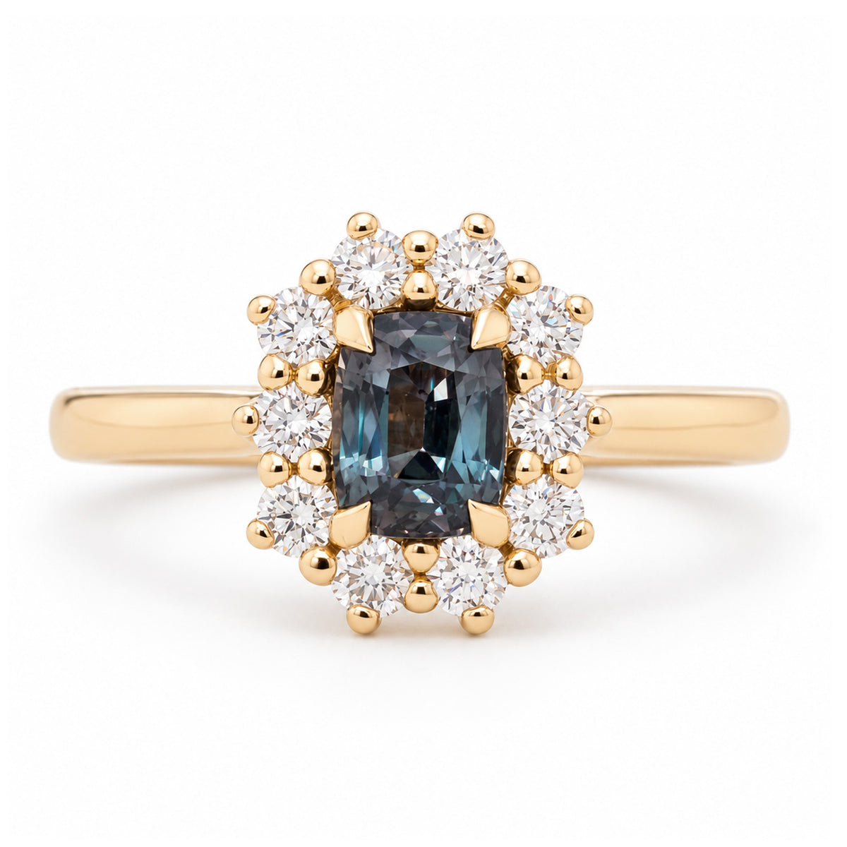 Antique-inspired blue sapphire and diamond cluster engagement ring in yellow gold, featuring a rectangular sapphire surrounded by brilliant-cut white diamonds.