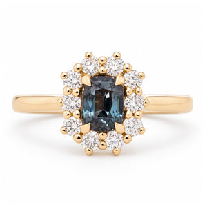 Antique-inspired blue sapphire and diamond cluster engagement ring in yellow gold, featuring a rectangular sapphire surrounded by brilliant-cut white diamonds.