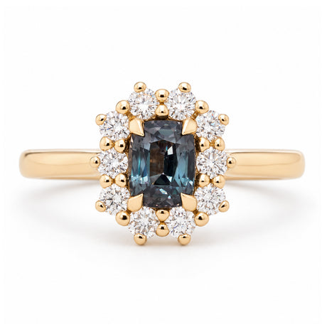 Antique-inspired blue sapphire and diamond cluster engagement ring in yellow gold, featuring a rectangular sapphire surrounded by brilliant-cut white diamonds.