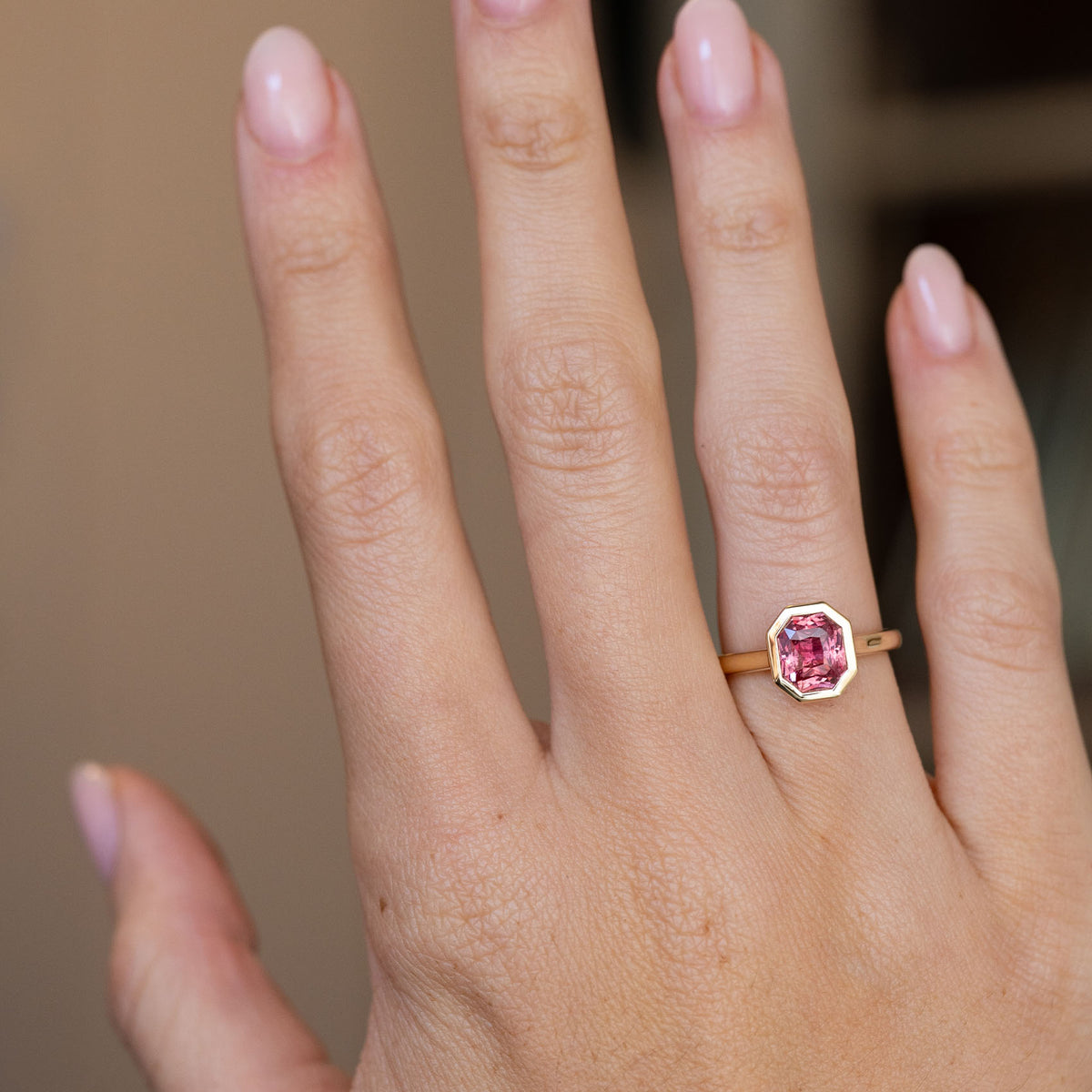 Peachy pink sapphire ring worn on the hand, displaying its elegant scale and warm vintage-inspired colour palette.
