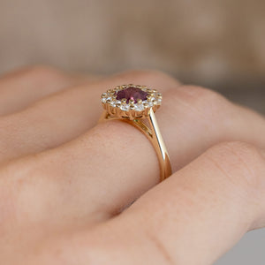 Side-angle view of the pink sapphire ring worn on a hand, highlighting the elevated cluster setting and delicate yellow gold band.
