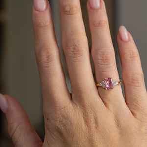 Vintage-inspired pink sapphire engagement ring worn on the hand, showing the elegant scale of its diamond-accented yellow gold design.