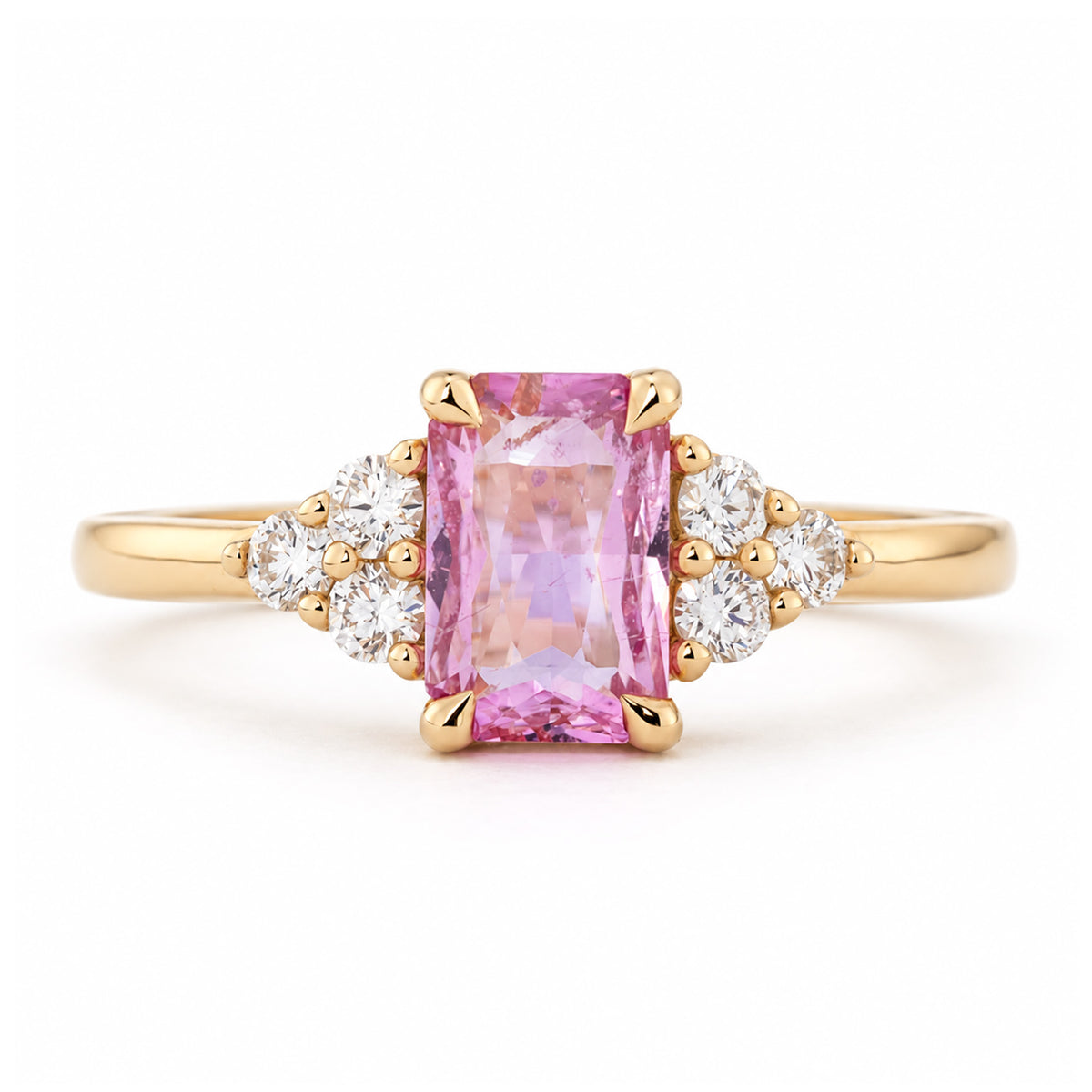 Vintage-inspired pink sapphire and diamond trefoil engagement ring in yellow gold, with a rectangular centre stone and clustered diamond shoulders.