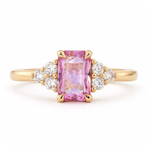 Vintage-inspired pink sapphire and diamond trefoil engagement ring in yellow gold, with a rectangular centre stone and clustered diamond shoulders.