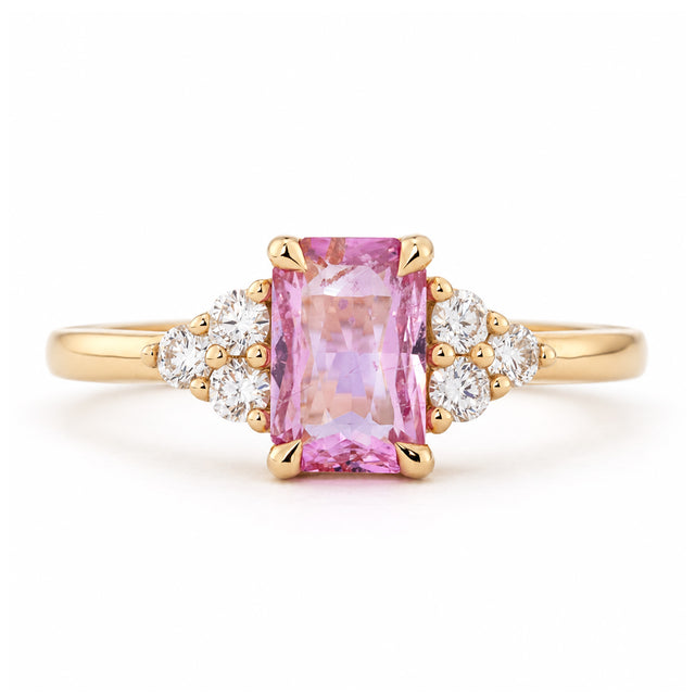 Vintage-inspired pink sapphire and diamond trefoil engagement ring in yellow gold, with a rectangular centre stone and clustered diamond shoulders.