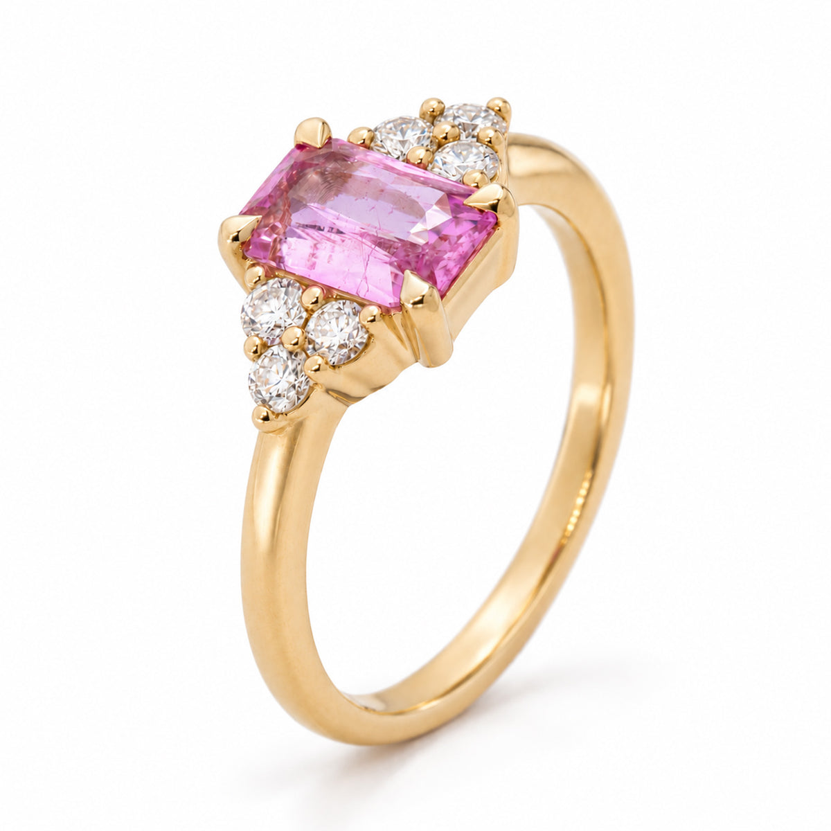 Elevated studio portrait of the pink sapphire ring, revealing its claw-set centre and trefoil diamond detailing on each side.