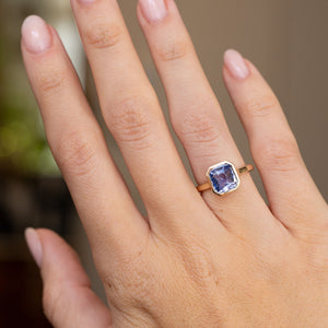 Antique-style sapphire engagement ring worn on the hand, displaying its elegant square silhouette and warm yellow gold frame.